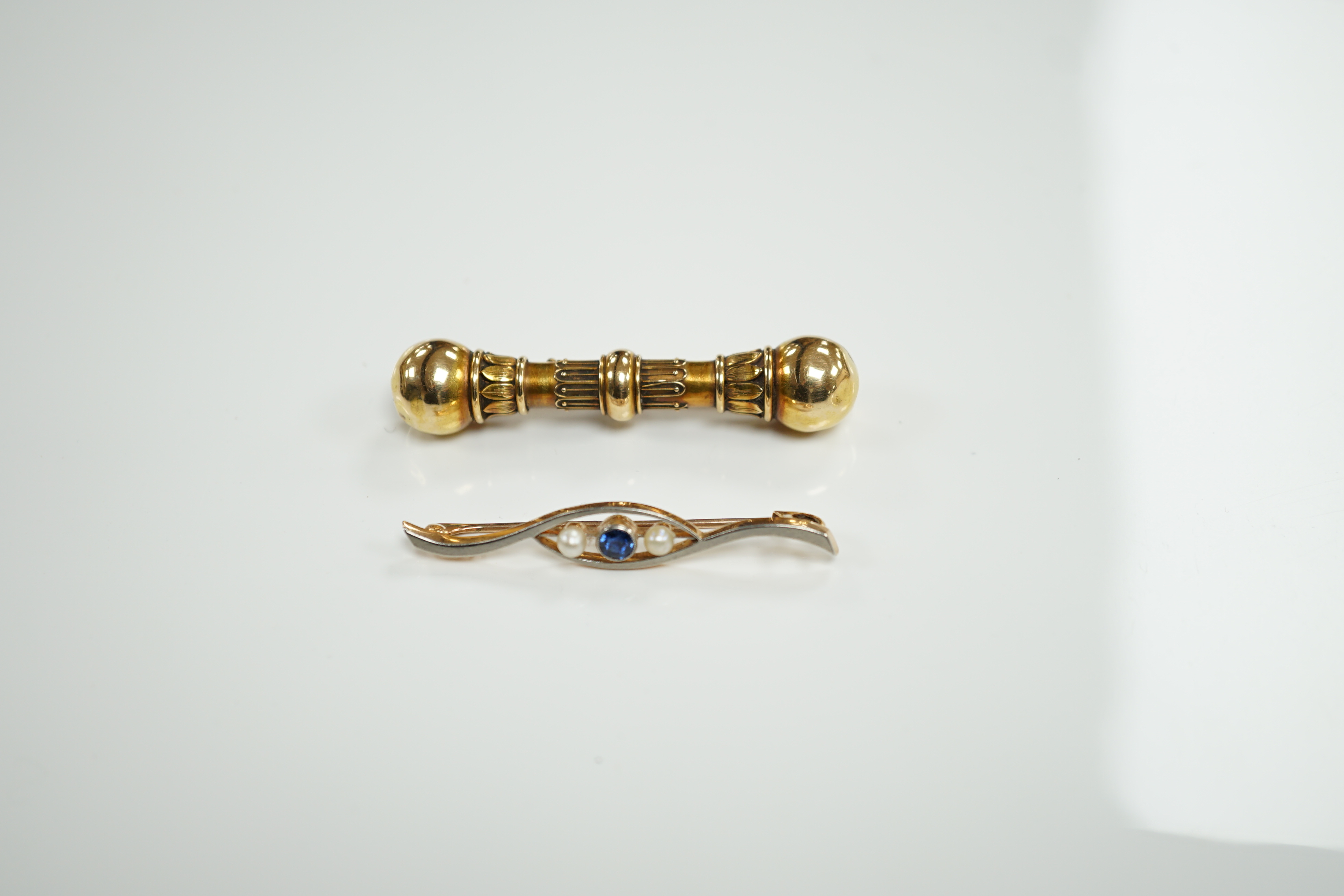 A Victorian yellow metal 'dumbbell' bar brooch, with engraved inscription dated 1862, 56mm and a later 15ct, sapphire and seed pearl set three stone crossover bar brooch.